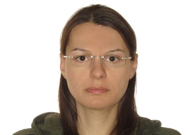 Joanna Rutkowska in an olive green hoodie and glasses against a white background.