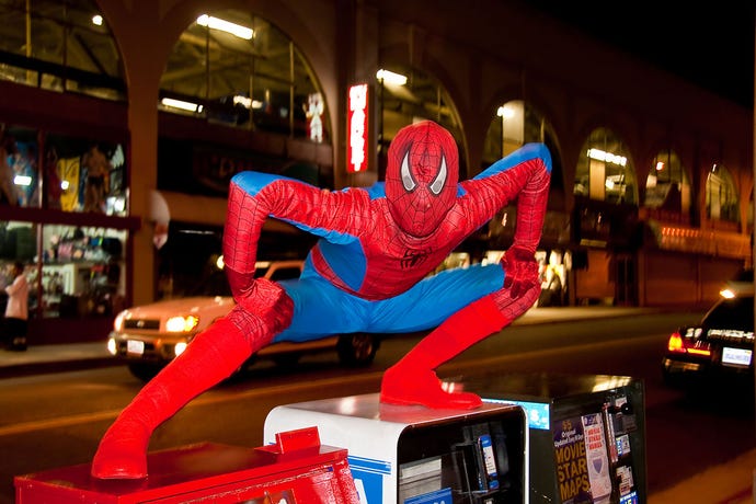 An off-brand Spider-Man impersonator strikes a pose on newspaper boxes on Hollywood Boulevard