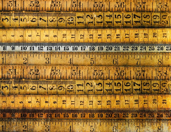 Antique rulers and measuring tapes lie horizontally across the image.
