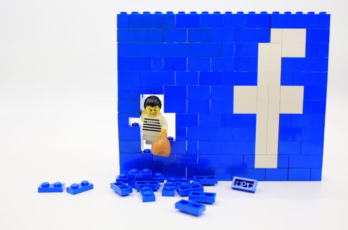 The Facebook logo made of Lego bricks with a burglar breaking through it
