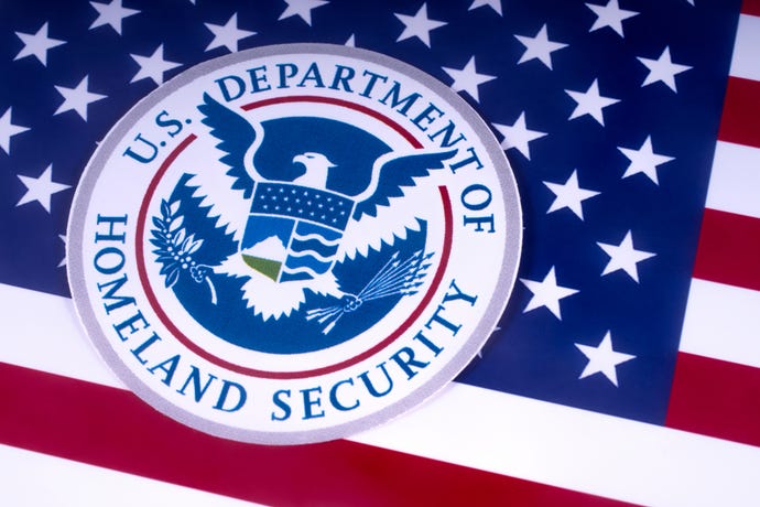 The symbol of the US Department of Homeland Security pictured over the USA Flag