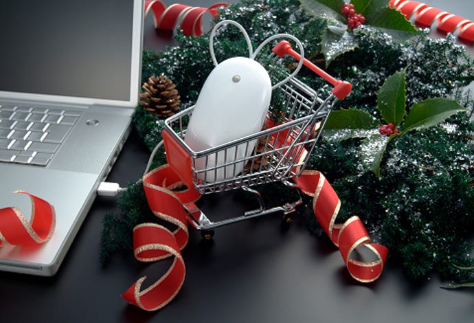 Laptop with holiday evergreen decorations and a mouse in a small shopping cart.