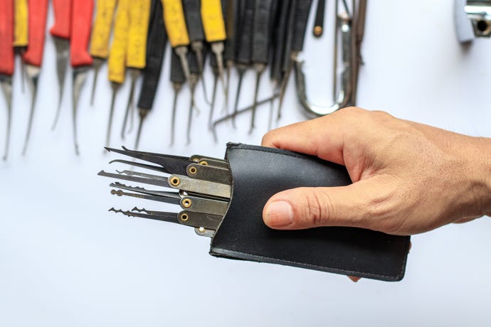 A person holding a set of lock picks against a background of other lock picks. 