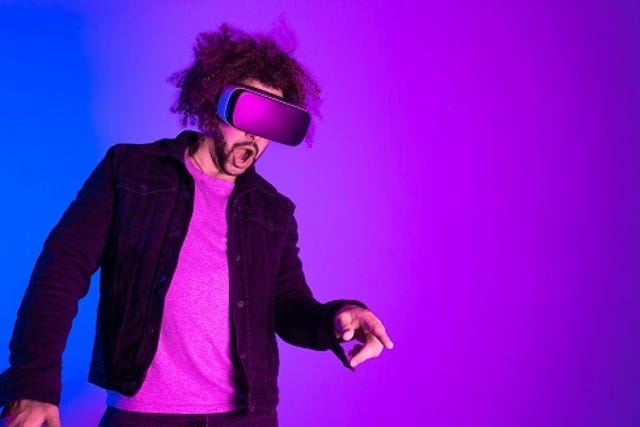 Metaverse concept. Surprised young man touching the air and smiling during VR experience