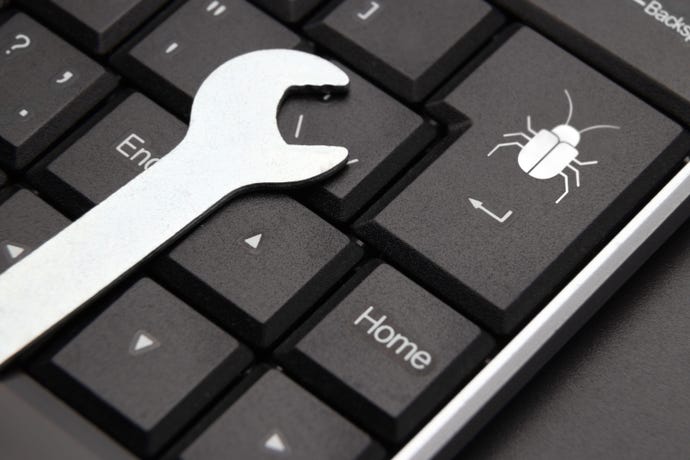 Wrench on keyboard next to button with a bug to illustrate a computer bug
