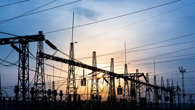 electric substation with power lines and transformers, at sunset