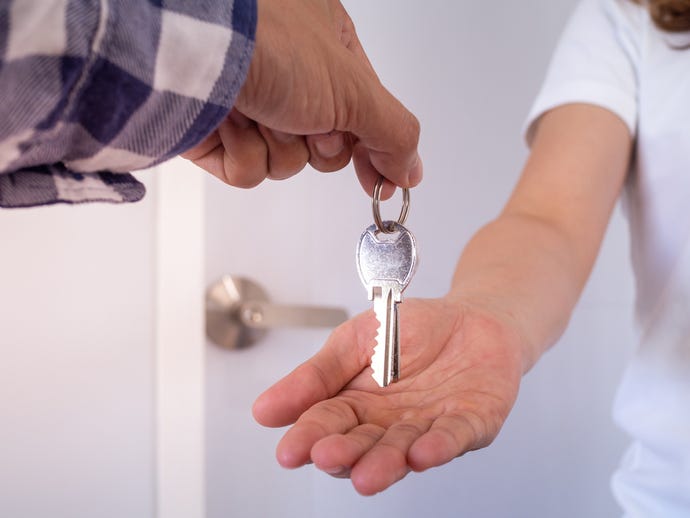 person handing over key to another individual