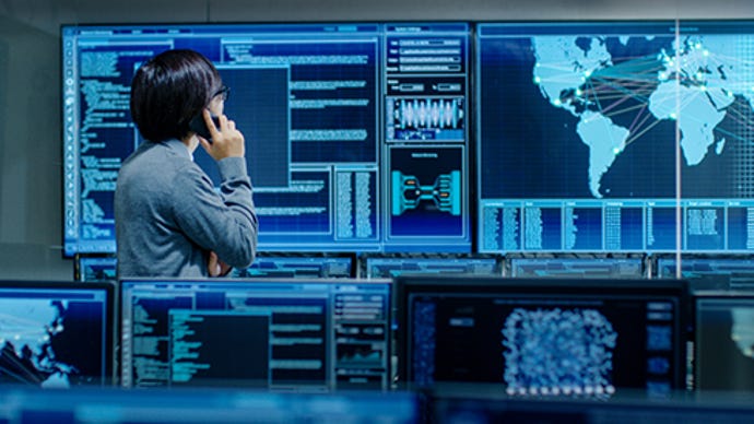 An IT Admin talks on the phone in the system control room of a high-tech facility used for surveillance, data mining, and AI.