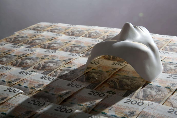 A white drama mask lies on a bed of currency
