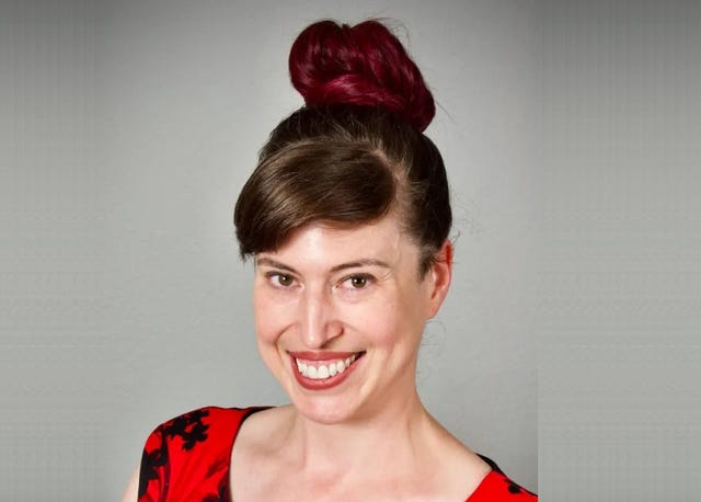 A brunette woman with a high updo and red and black dress.