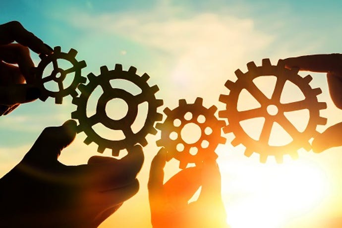 Four big gears held up against a cloudy sky.