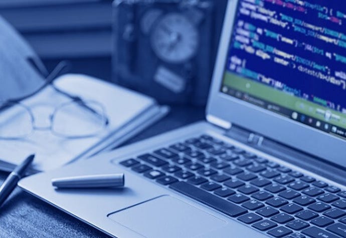 A laptop with a pen on it and source code on the screen.