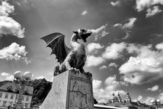 The Dragon statues at the Dragon Bridge and Cathedral of St. Nicholas at the background in center of Ljubljana, Slovenia