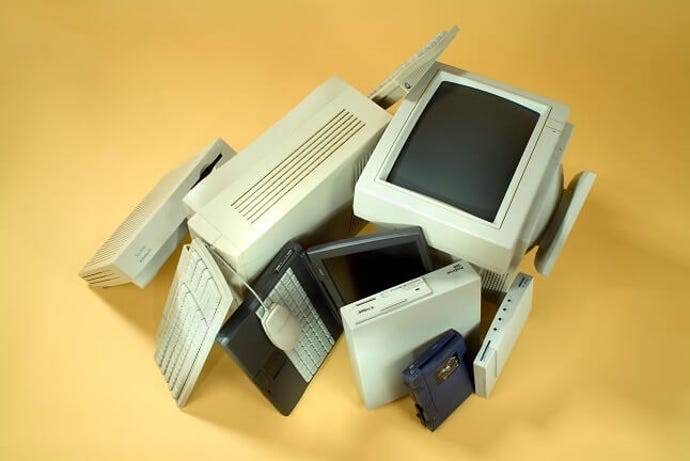 bunch of used computers in a pile with a yellow background