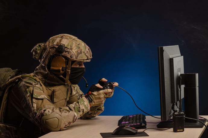 Soldier playing a game on a desktop computer and holding controller