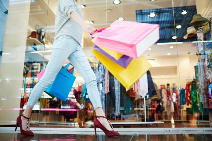 An individual shopping in stores with multiple bags already purchased.