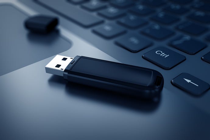 Image shows an uncapped  black USB drive sitting on the keyboard of an open, black laptop computer next to the CTRL key