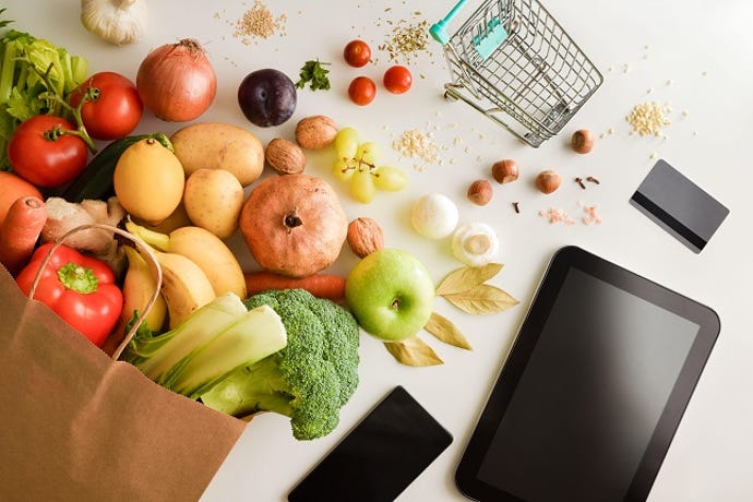 fruits and vegetables with a tiny grocery cart and a shopping app on mobile phone