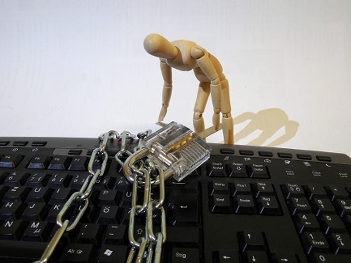 A wooden posing dummy leans over a keyboard that is wrapped with a padlocked chain