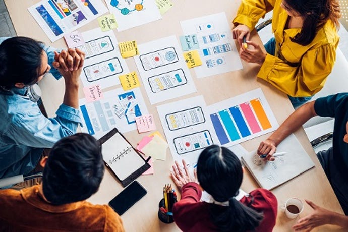 An overhead photo of people examining printed mockups of user interface designs