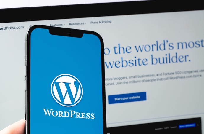 WordPress logo mobile app on screen smartphone iPhone with Macbook display closeup