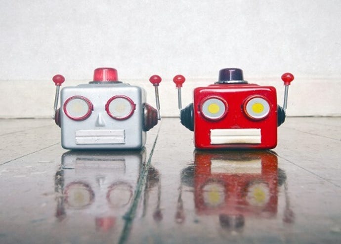 Photo of two toy robot heads, one silver and one red, sitting on a table