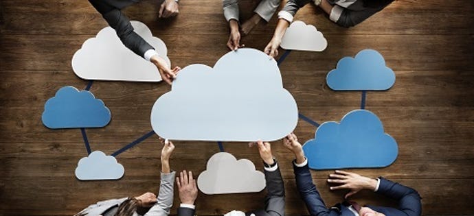 cut-out clouds on a desk with many hands moving them around