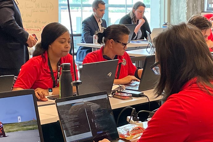 Ohio Cyber Reserve test their incident response skills; three women in red shirts, with a man and woman in suits in background