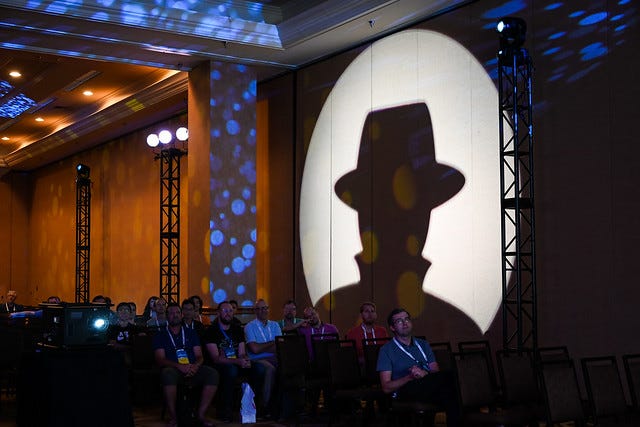 Photo of the audience at the 2019 Pwnie Awards at Black Hat USA, with projected silhouette of Black Hat logo on wall