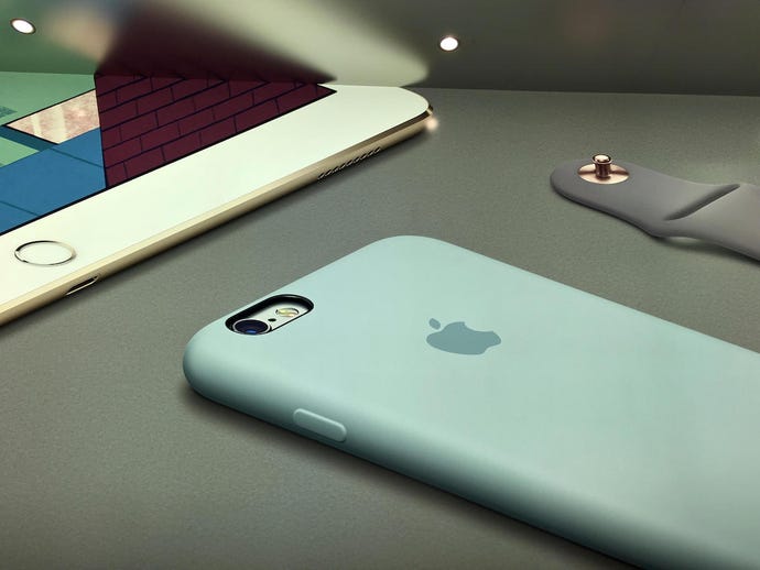 an iPhone, an iPad, and the wrist band of an Apple Watch laying on a surface.