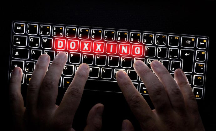 hands typing on a lit up keyboard that spells out the word "Doxxing"