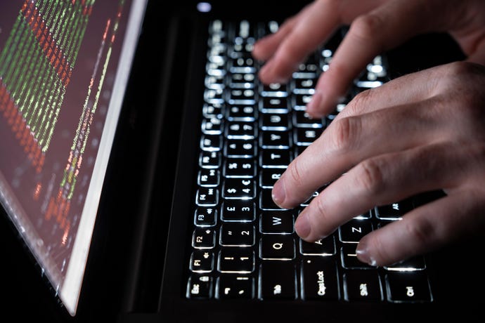 Close-up of someone typing on a dark computer to illustrate hacking