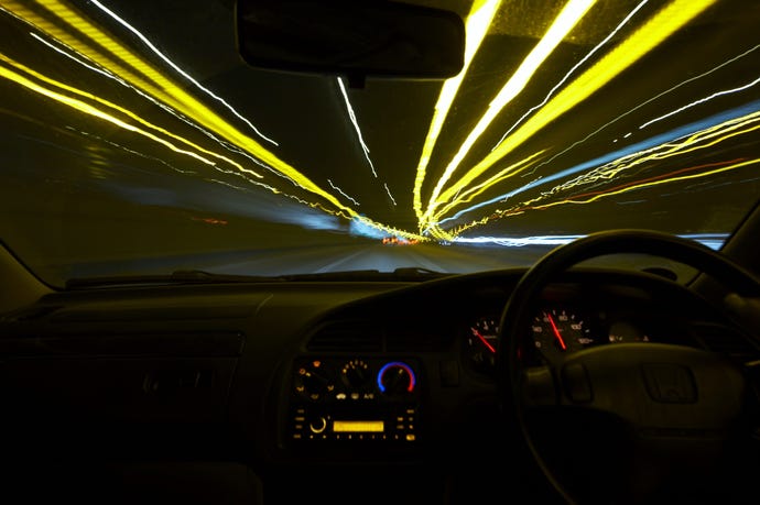 dashboard of a car driving through a tunnel at night with speed motion light trails
