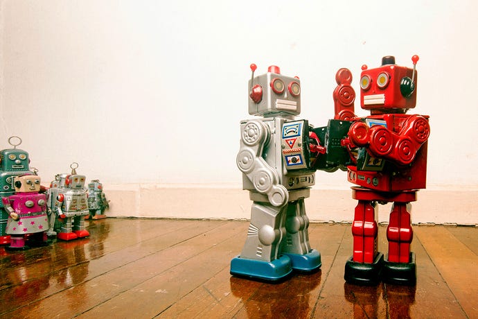 Two toy robots engage in fisticuffs while a small crowd of toy robots watch