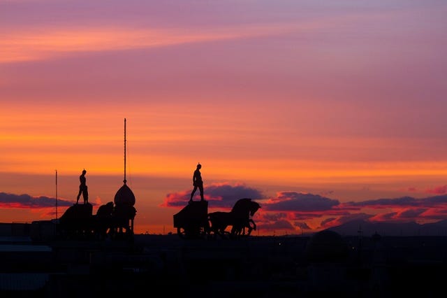 Silhouettes of the statues situated on the roofs of Madrid, Spain, at sunset