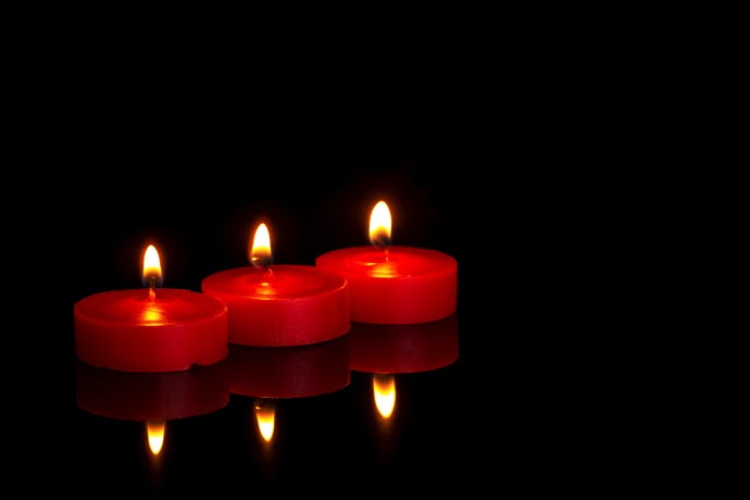 three red candles burning against black background