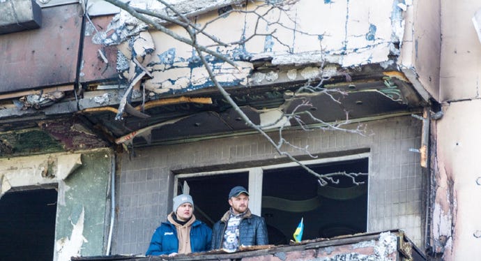 Two young men standing in the balcony of a building nearly destroyed by a bombing in Kyiv, Ukraine.