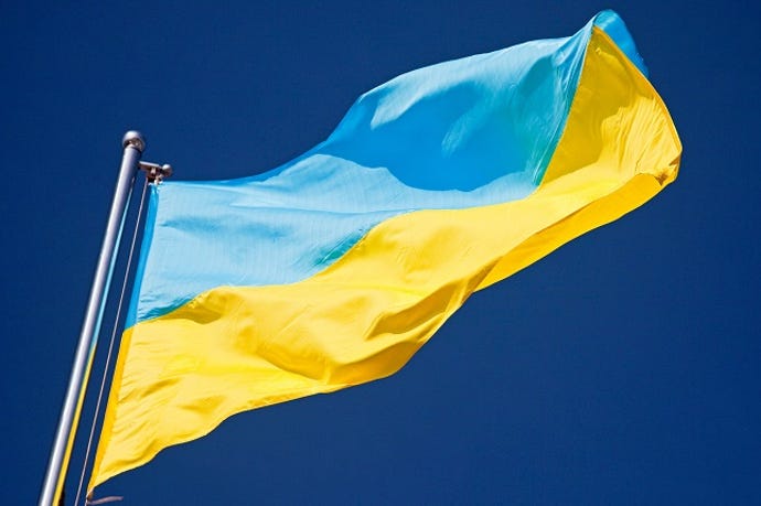 Image shows a blue and yellow Ukrainian flag flying on a flagpole in the wind
