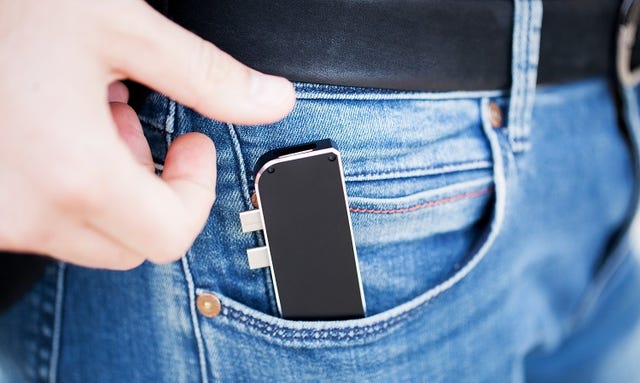 A hand putting a USB stick in a pocket
