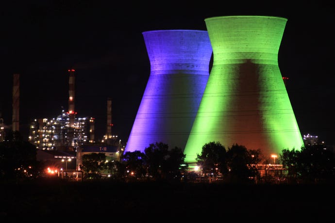 Cooling towers at BAZAN in Haifa at night with the towers lit in green and purple light