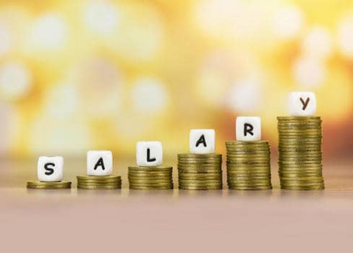 salary text block with stacked coins on blurred background