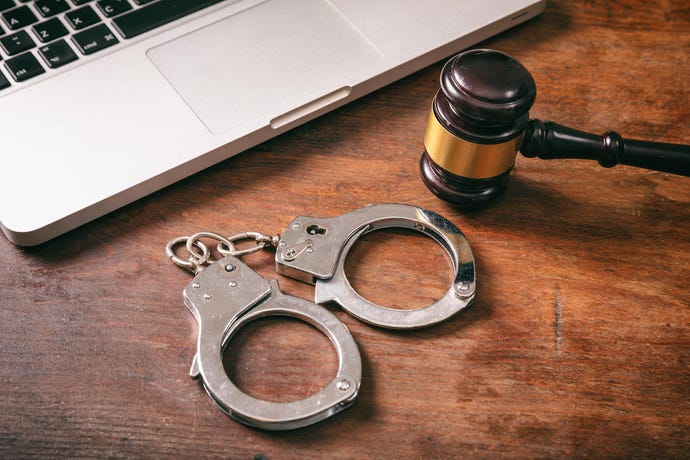 gavel and handcuffs next to keyboard on wooden surface