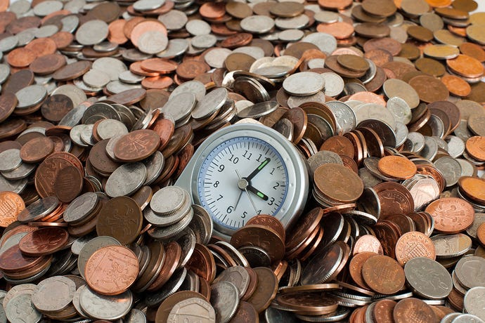 Photo of a desk clock resting in a large pile of assorted coins
