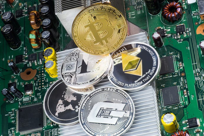 Different cryptocurrency coins stacked atop a computer motherboard