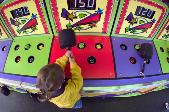 A small child plays whack-a-mole at a carnival