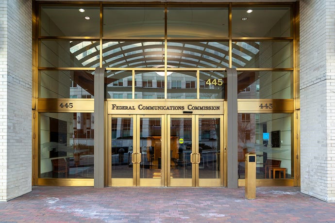 Entrance to Federal Communications Commission office in Washington, DC; glass doors, white brick walls, brass fittings