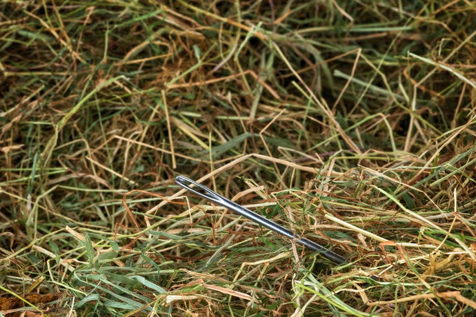 Closeup photo of a sewing needle sticking out of a pile of hay
