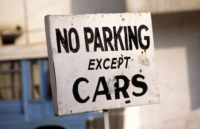 An image of a white sign that reads "no parking except for cars" in black lettering.