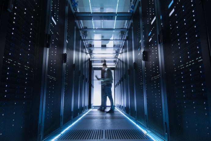 Man standing in a dark corridor surrounded by backup servers