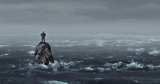 A man stands alone on a rock amid ocean waters